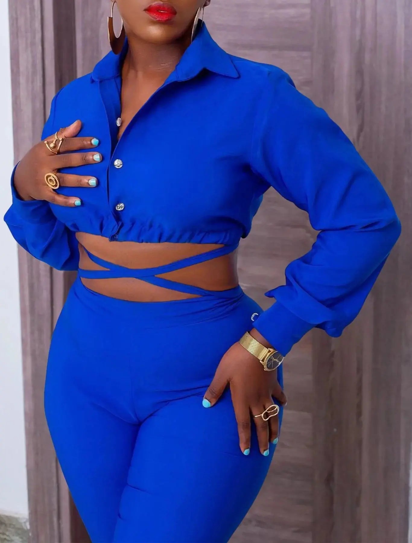 Woman wearing a blue outfit with a cut-out design, standing against a neutral background.
