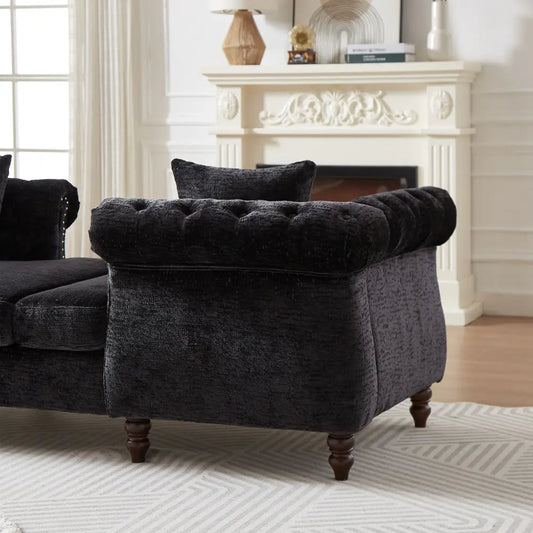 Black tufted armchair in a living room with a fireplace.