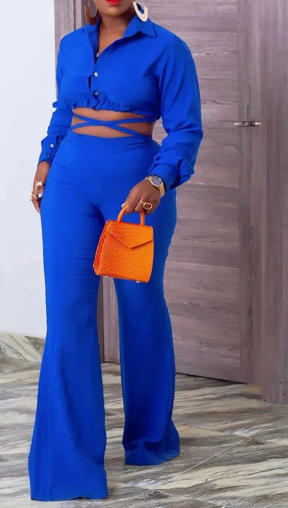 Woman in a blue outfit holding an orange handbag indoors.