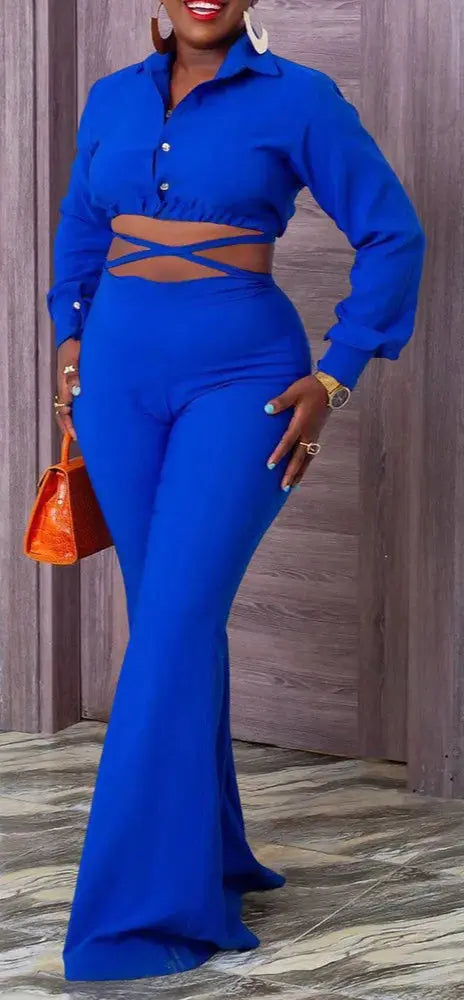 Woman wearing a blue outfit with a cut-out design, standing against a wooden panel background.