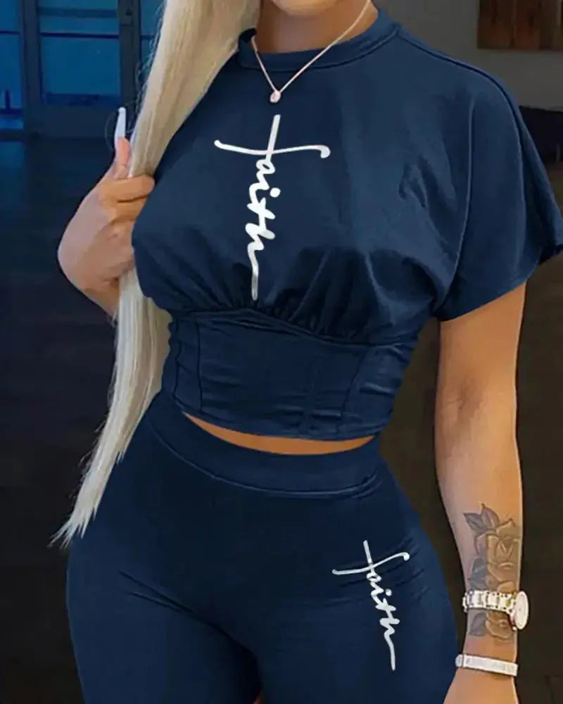 Person wearing a navy blue outfit with 'faith' printed on it, standing indoors.
