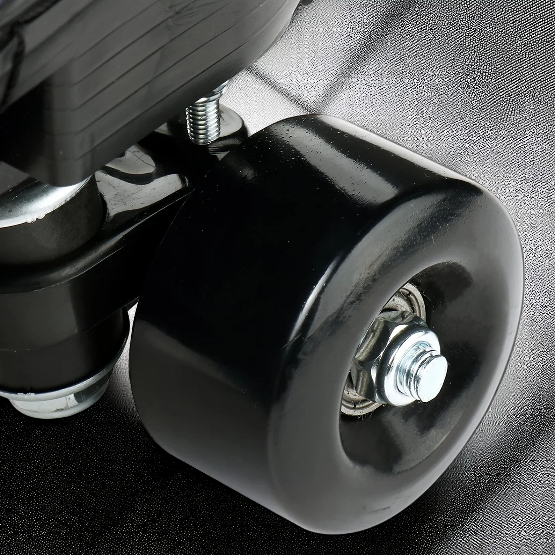 Close-up of a black wheel with metal bearings on a textured surface