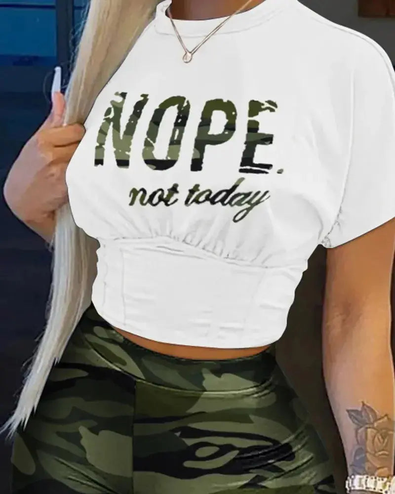 Person wearing a white crop top with 'NOPE not today' text and green camouflage leggings.