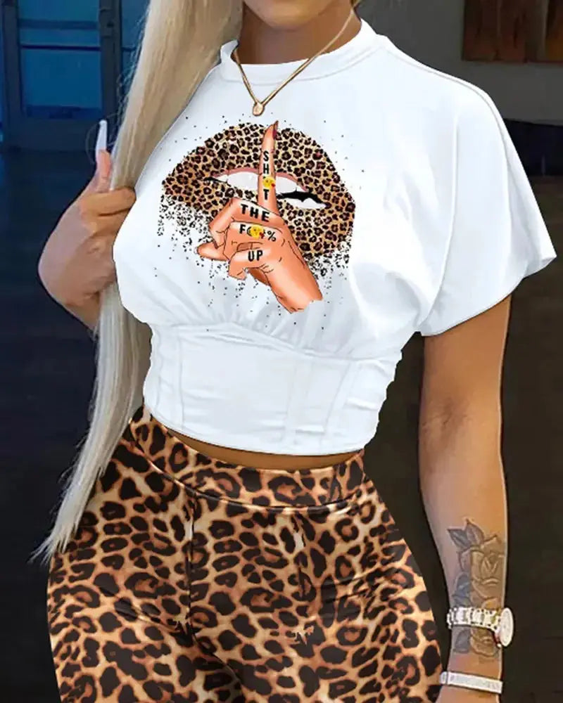 Person wearing a white t-shirt with a graphic design and leopard print pants.