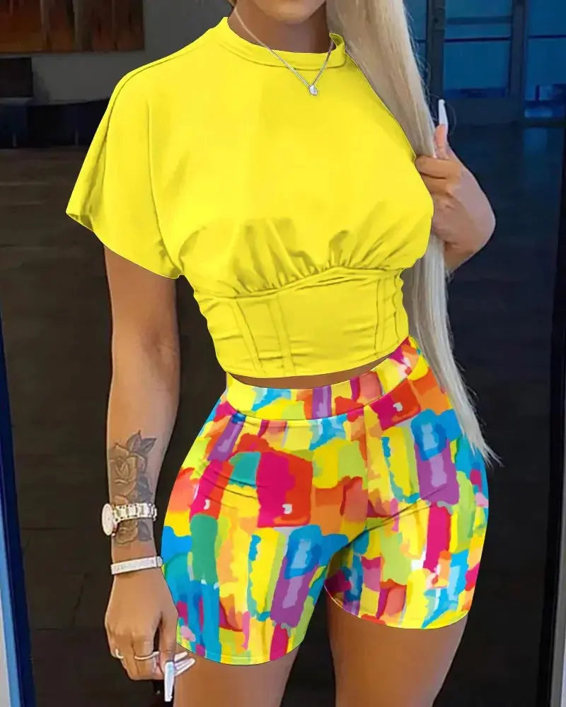 Person wearing a bright yellow top and colorful shorts indoors.