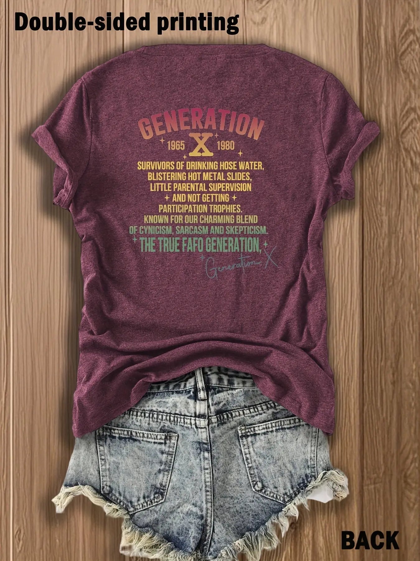 Maroon t-shirt with text on the back displayed on a wooden surface