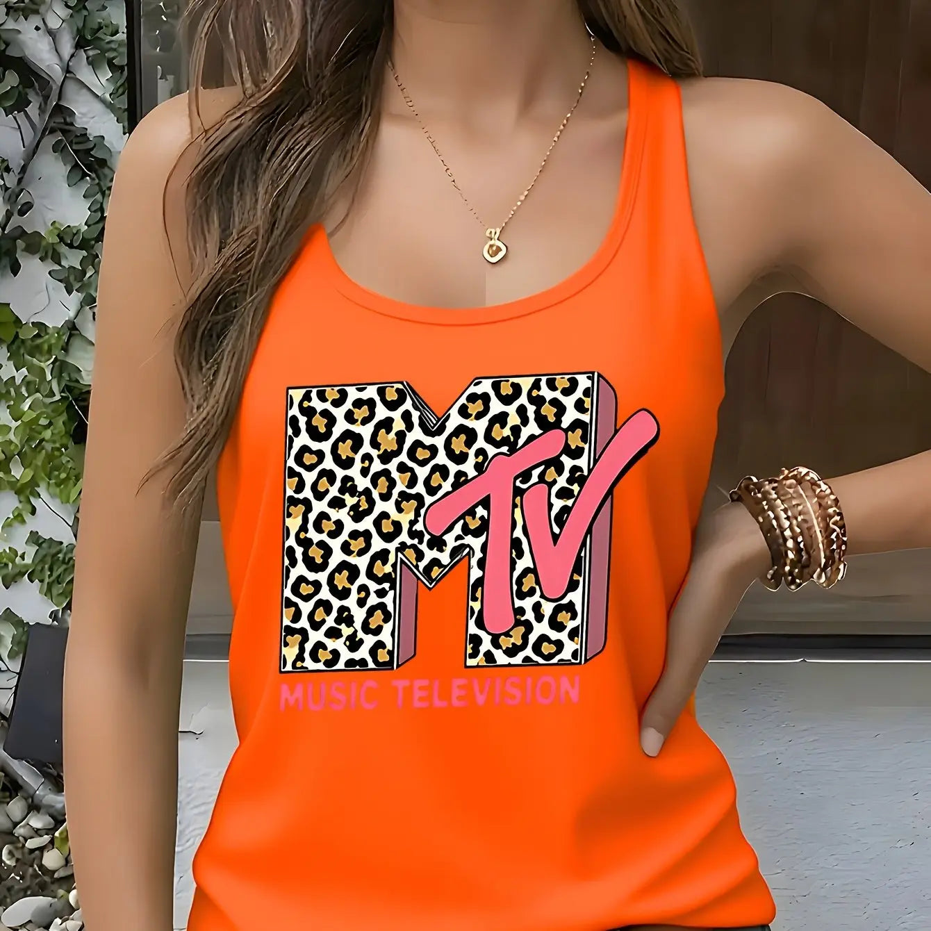Model wearing the Fantascticz 80s style racerback tank top in a bold, vibrant orange, featuring the iconic MTV Music Television logo with a wild leopard print fill.