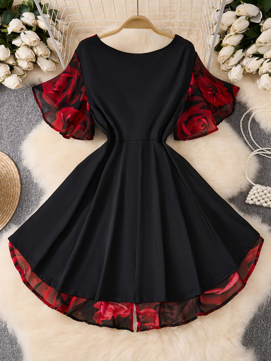 Black dress with red floral sleeves and hem on a hanger