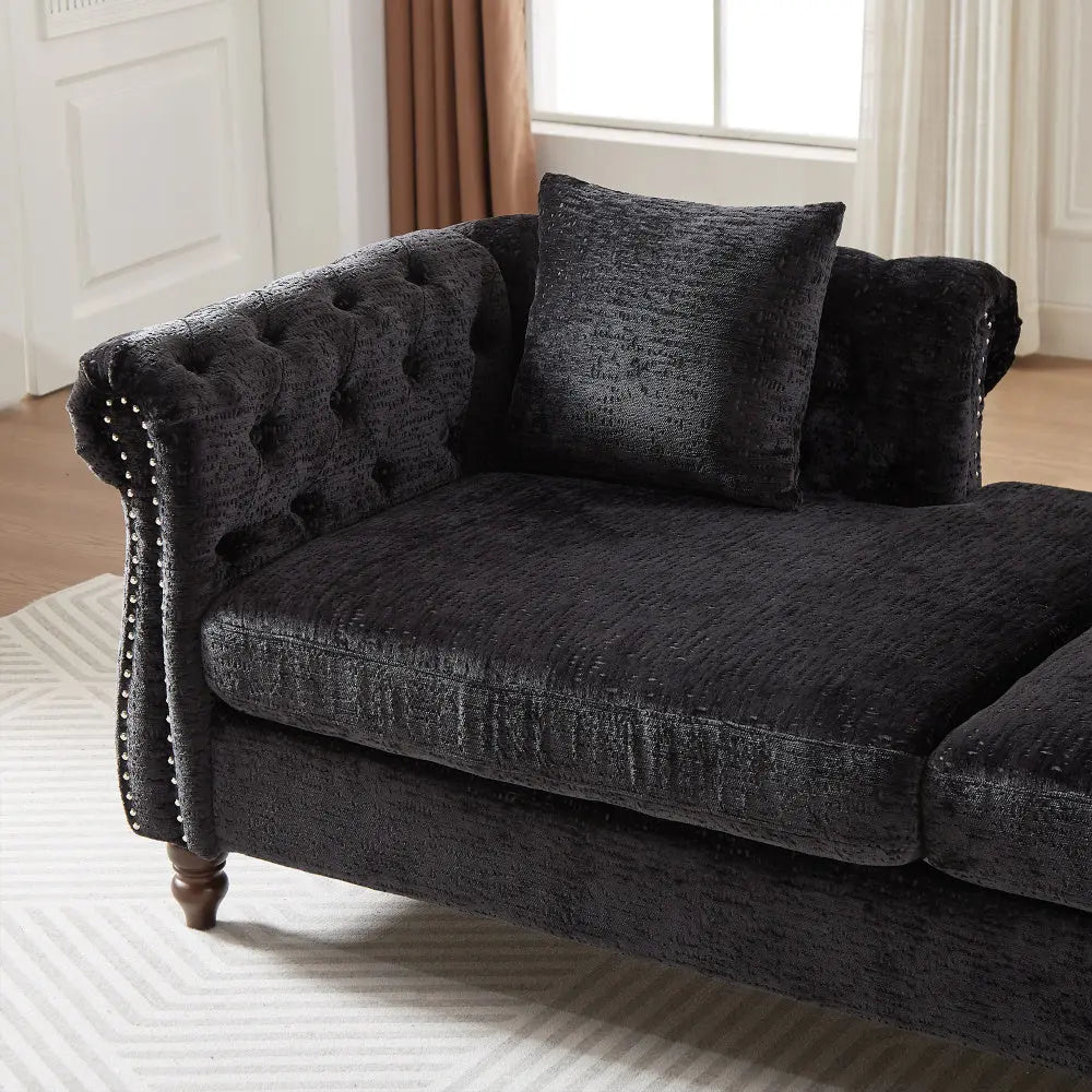 Dark gray tufted sofa with decorative pillows in a room with a window and curtains.