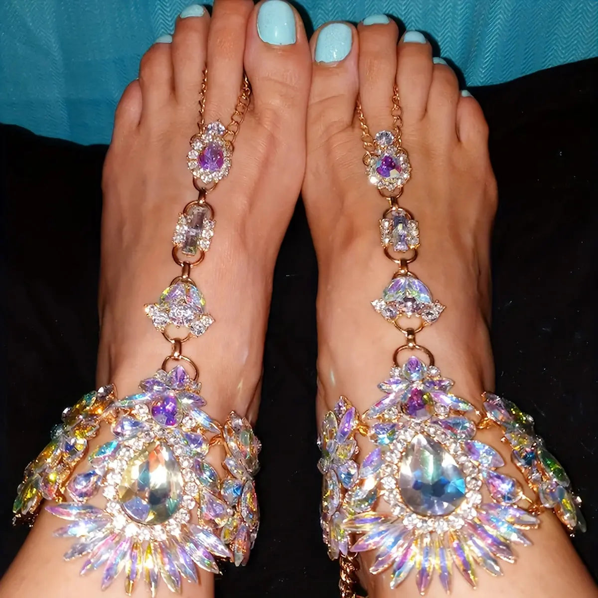 Top-down view of a model wearing The Aurora barefoot sandals on both feet, styled with light blue nail polish against a dark blue background.