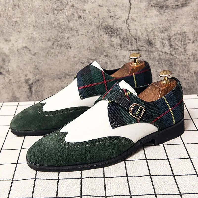 Product view of The Sterling Monk Strap shoes in the green plaid colorway. The design features a green suede toe cap, white leather vamp, and a classic plaid monk strap, displayed on a white grid-tile surface.