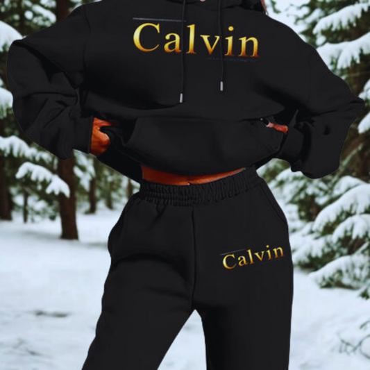 Person wearing a black Calvin hoodie and pants in a snowy forest setting