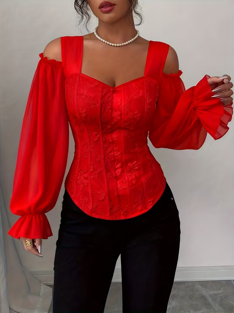 Woman wearing a vibrant red corset-style blouse with a sweetheart neckline, off-the-shoulder long sleeves, and a shirred bodice, paired with black pants.