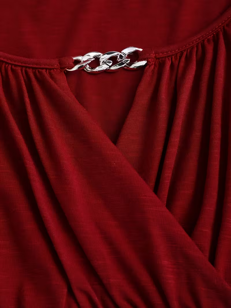 Close-up of a red garment with a silver chain detail.