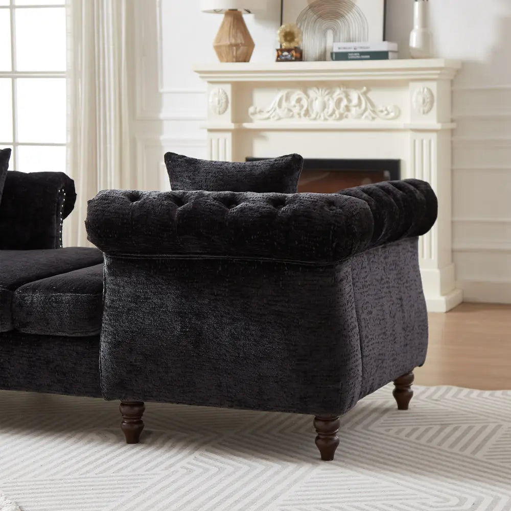 Black tufted armchair in a living room with a fireplace.