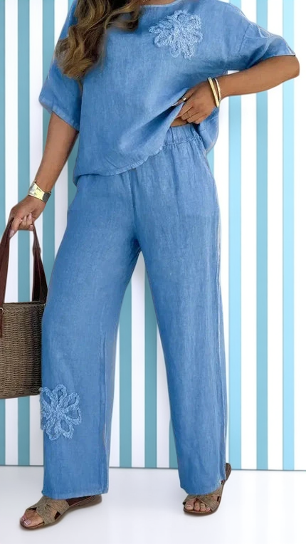 Person wearing a blue outfit with floral embroidery against a striped background