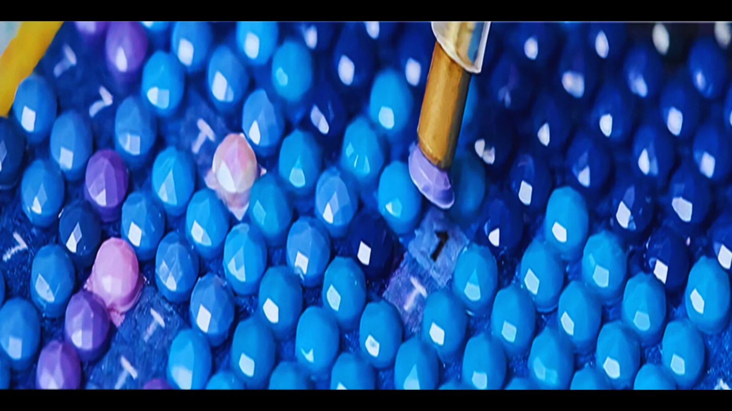 Close-up of blue and purple beads with a needle penetrating one bead.