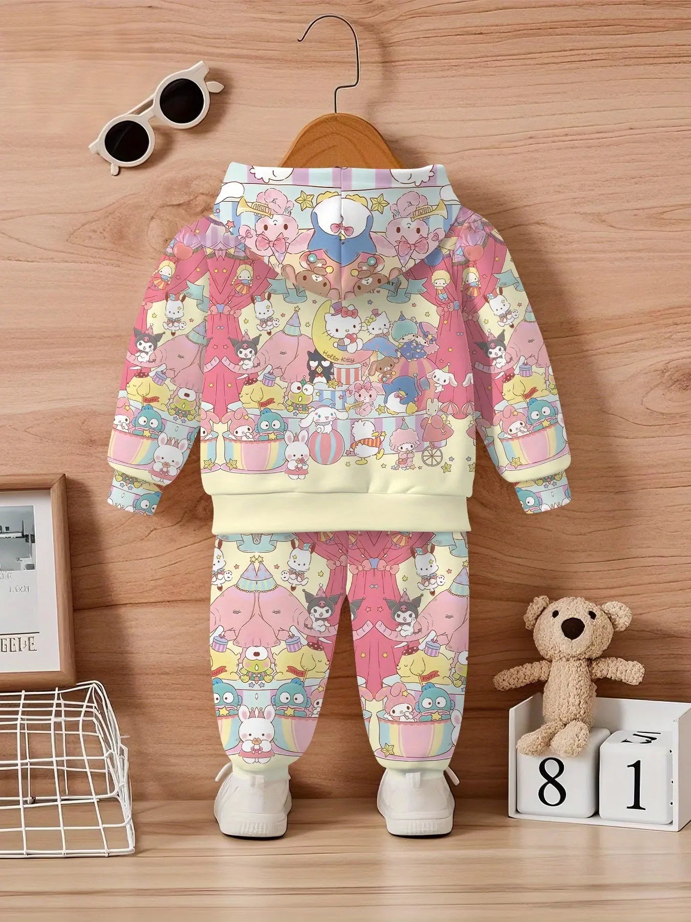 Children's hoodie and pants set with cartoon design on a wooden floor.