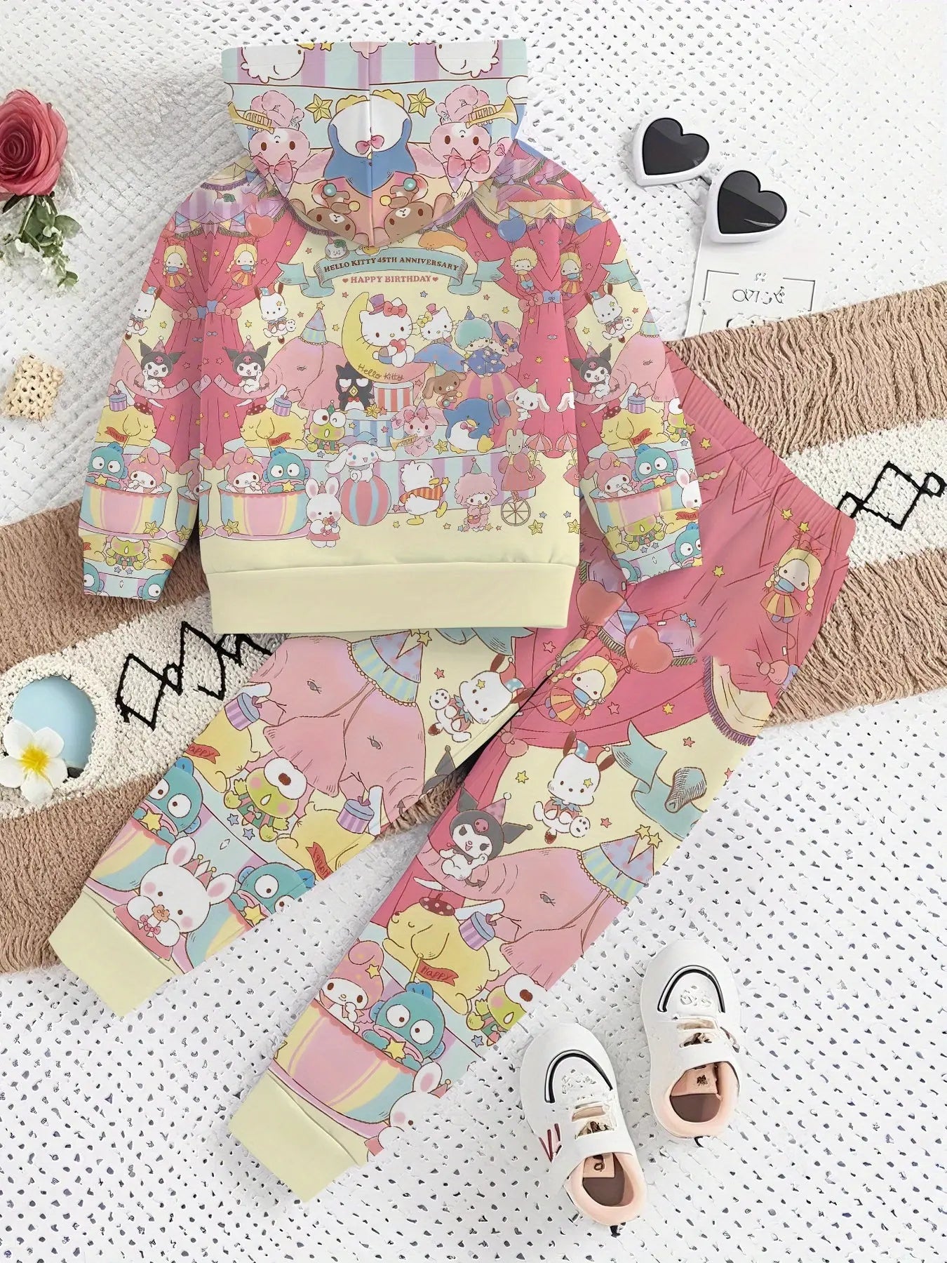 Children's hoodie, pants, socks, and shoes with cartoon character design on a textured surface.