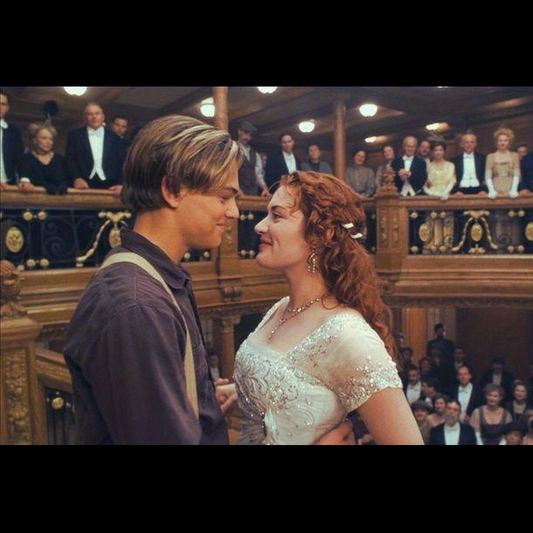 Two people in formal attire on a ship with a crowd in the background