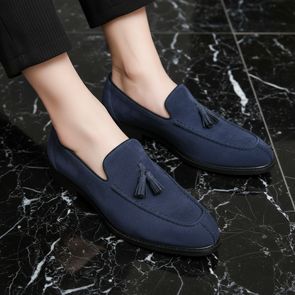 Navy loafers with tassels on a black marble floor
