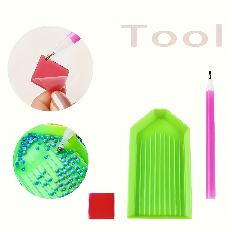 An image displaying the essential tools for a diamond painting kit. It includes a pink applicator pen, a green grooved tray for holding the drills, and a red square of wax for the pen tip. Two circular insets demonstrate how to load the pen with wax and pick up the diamond drills.