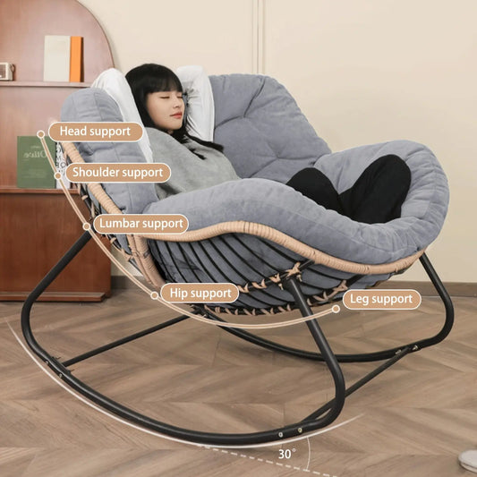 A person relaxing in The 'Oasis' Ergonomic Rocking Lounger from Fantascticz, with callouts highlighting the chair's full-body ergonomic support for the head, shoulders, lumbar area, hips, and legs.