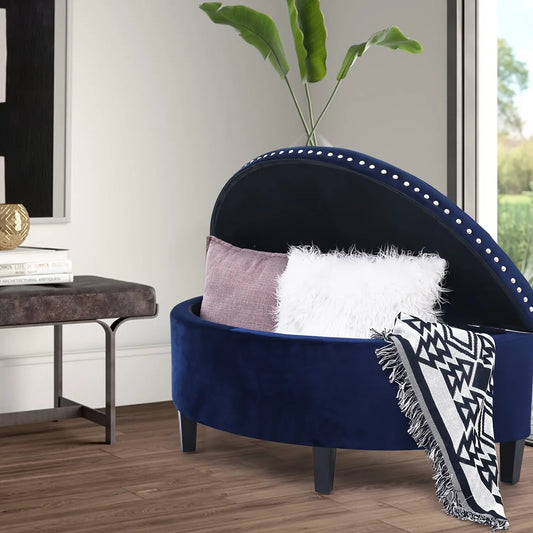 The Rhythm Velvet Storage Ottoman by Fantascticz in rich navy blue, with its lid open to display the spacious storage inside. Elegant silver nail head trim lines the top, adding a touch of glam to this functional piece.