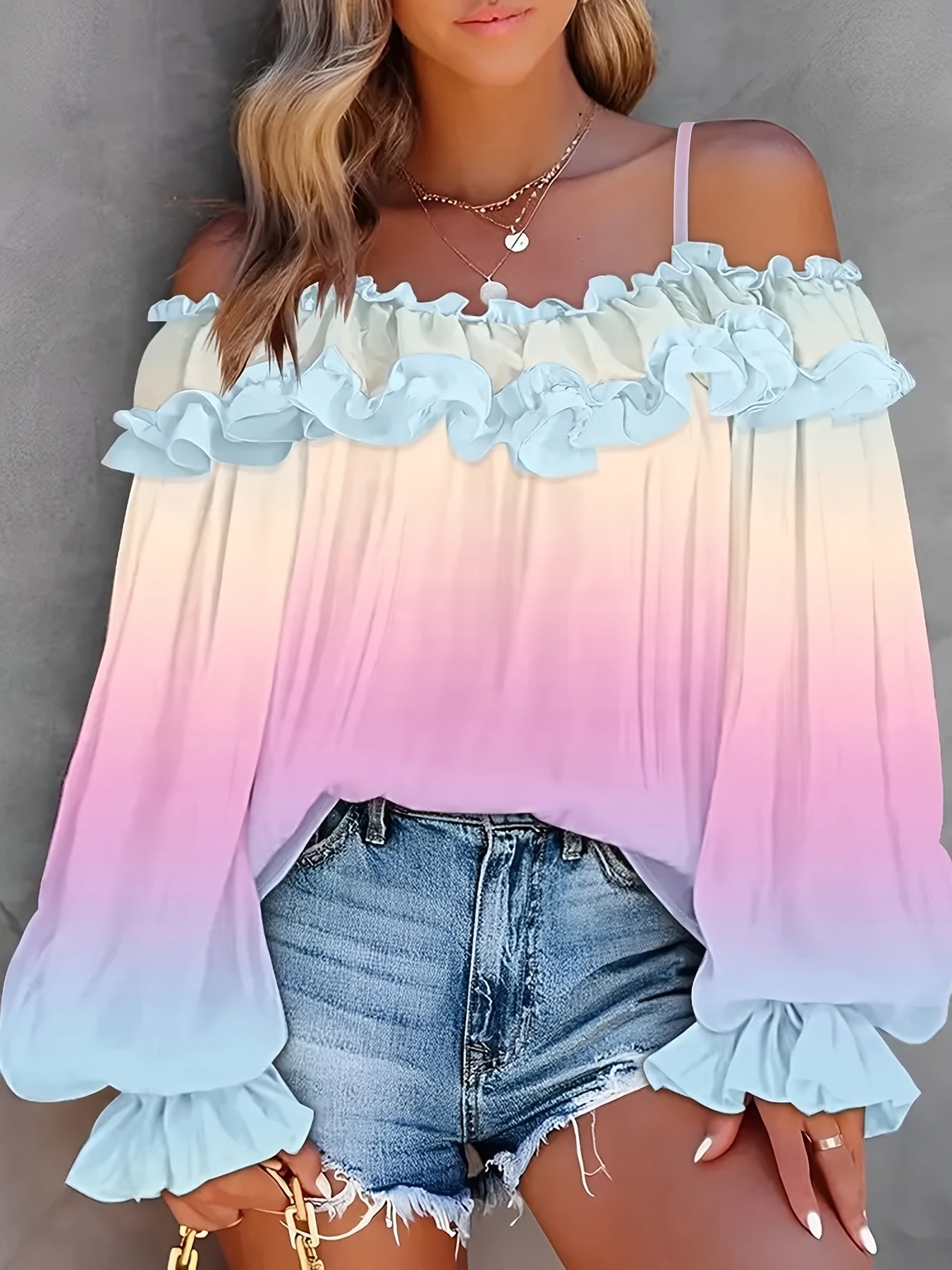 Woman wearing a gradient off-shoulder top with ruffled sleeves and denim shorts on a gray background
