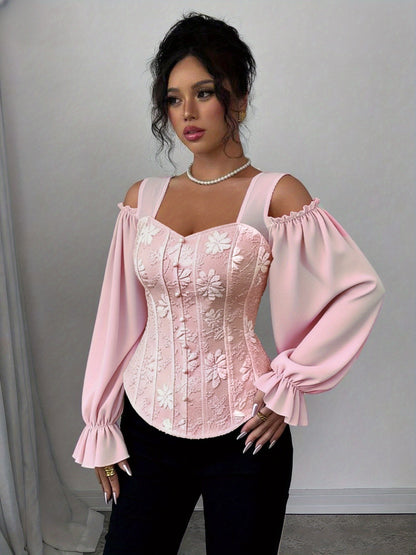 A woman wearing a pink lace corset style top with long sleeves against a plain background